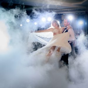 Groom whirls bride in the smoke dancing for the first time